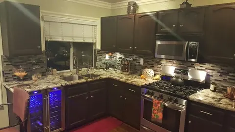 Dark kitchen cabinets with mosaic tile backsplash installed by Rocca Tile